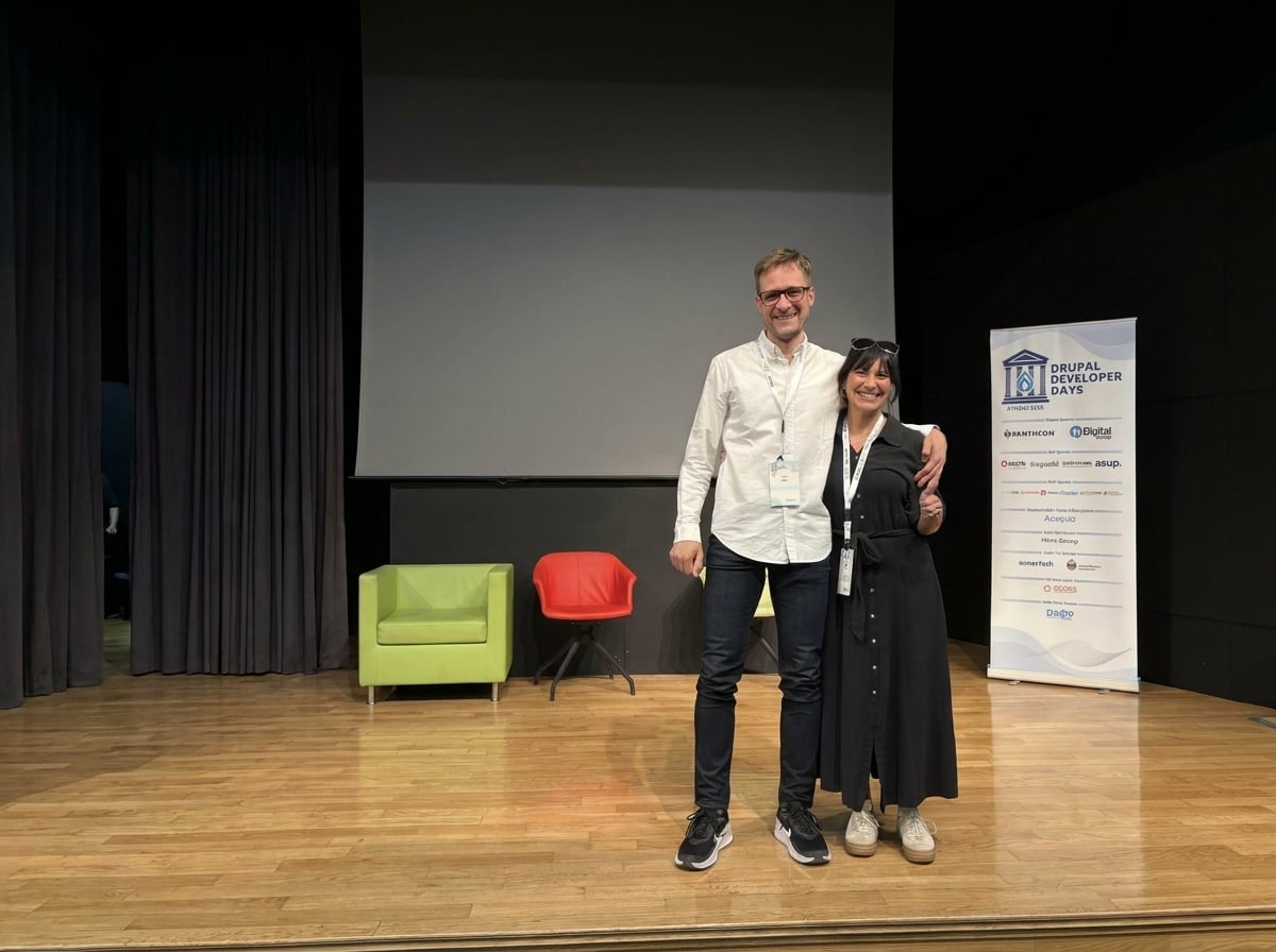 Two people posing on stage at Drupal Developer Days conference event.