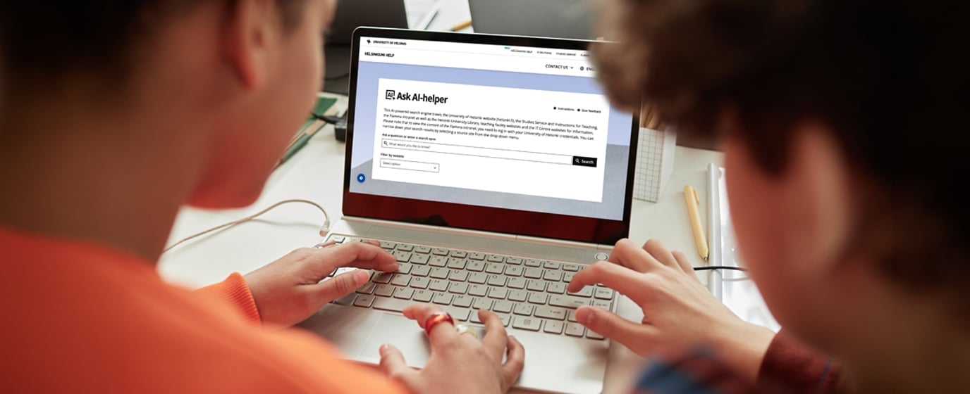 Two people viewing an "Ask AI-helper" webpage on a laptop screen.