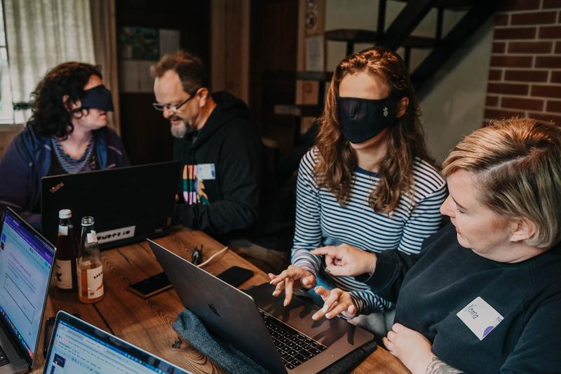 A person assisting another person that has a blindfold to use a computer