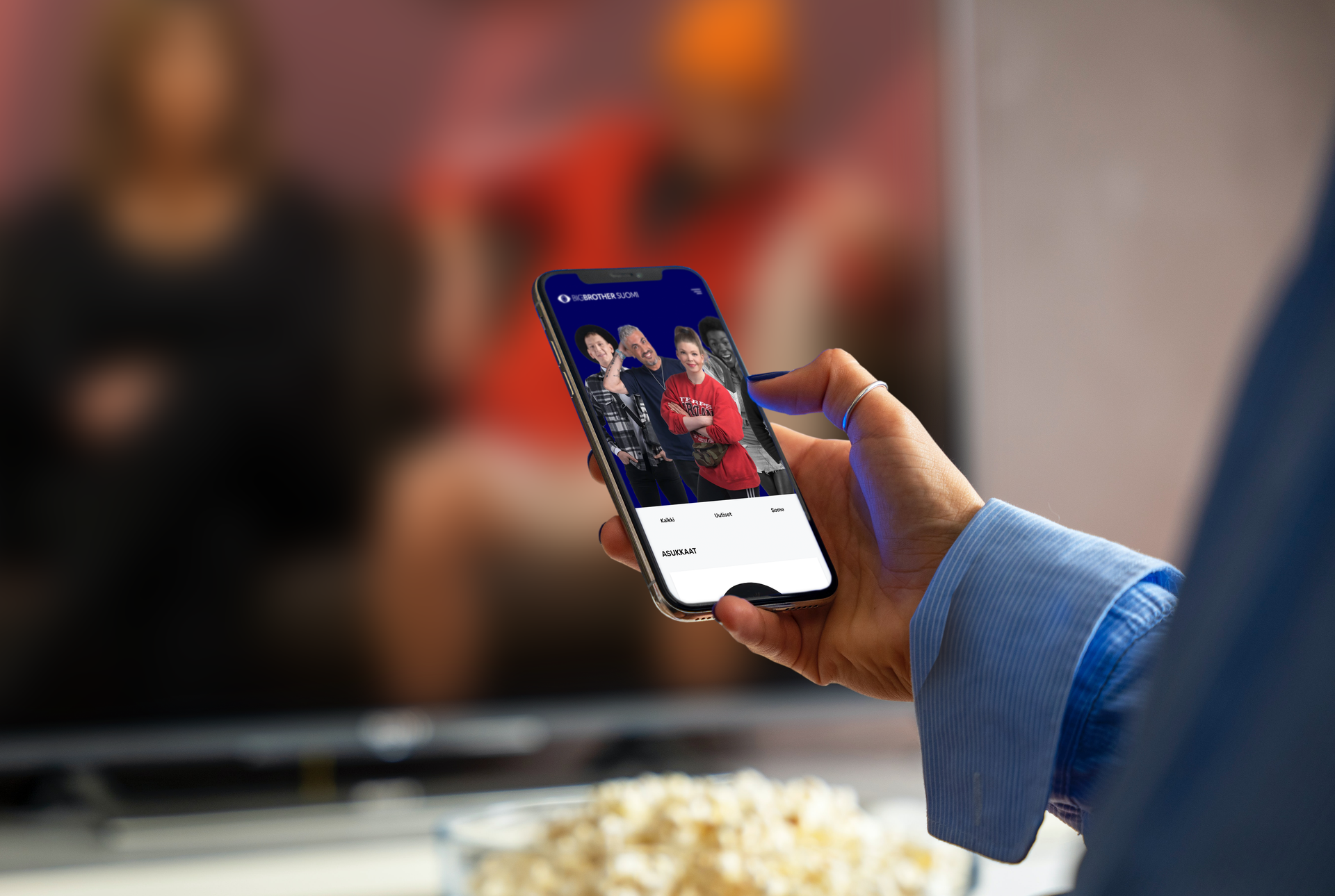 Person holding a mobile device with bigbrother.fi -site visible on the screen.