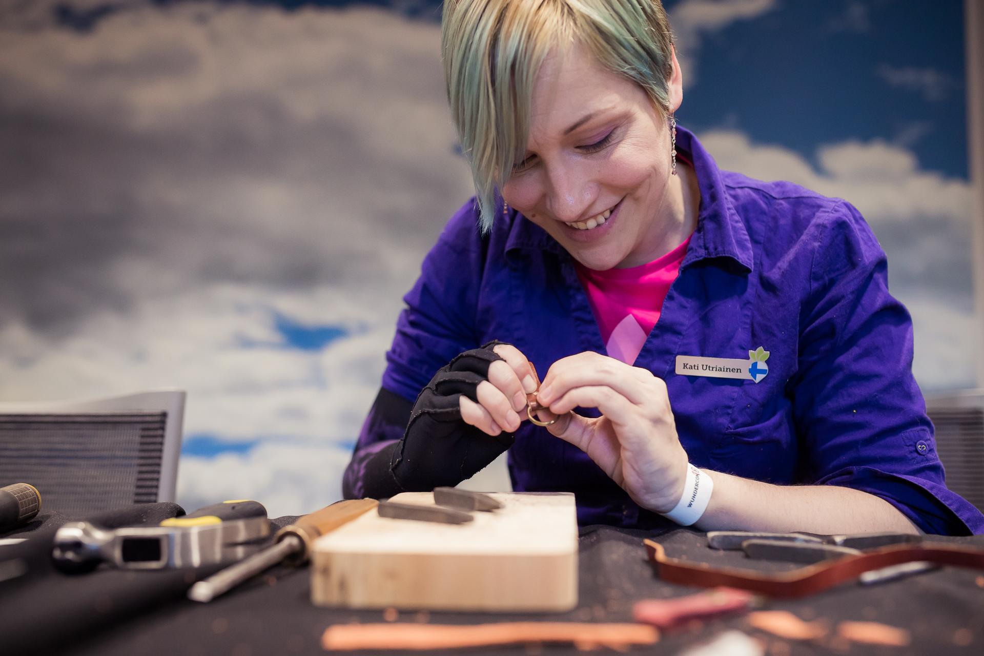 A smiling person creating a keychain at a workshop