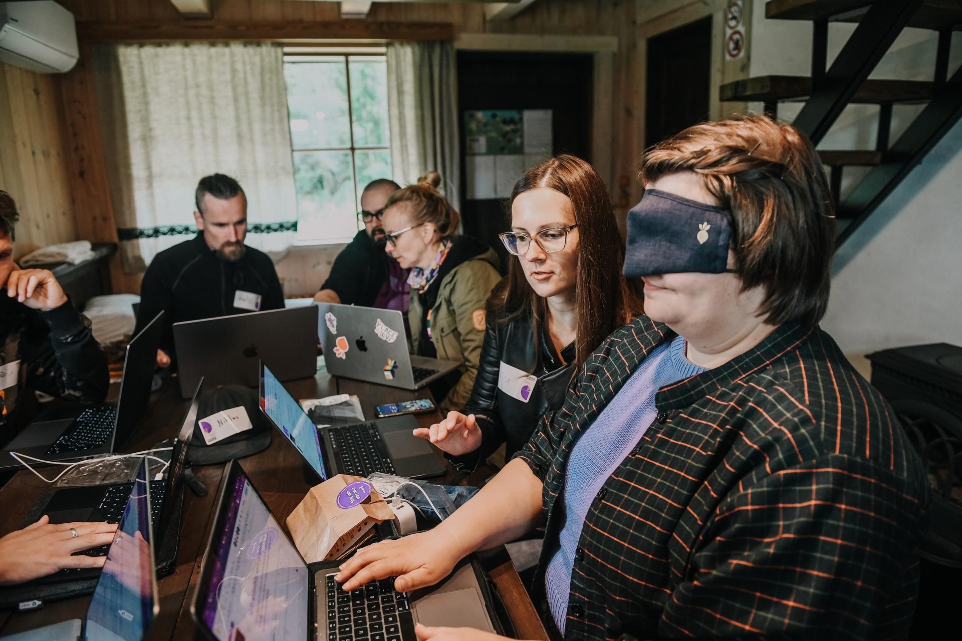 Blindfolded person typing on a computer while other person is giving instructions.