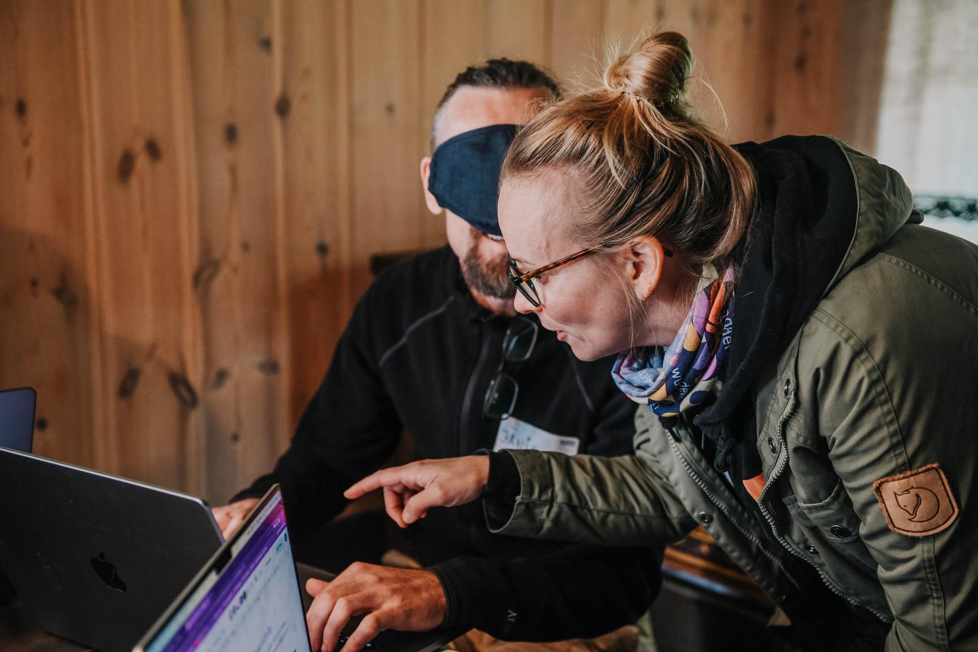 Blindfolded person typing on a computer while other person is giving instructions