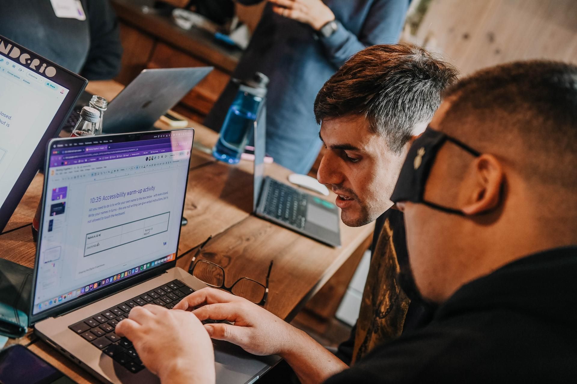 A man is typing blindfolded and another man is giving instructions