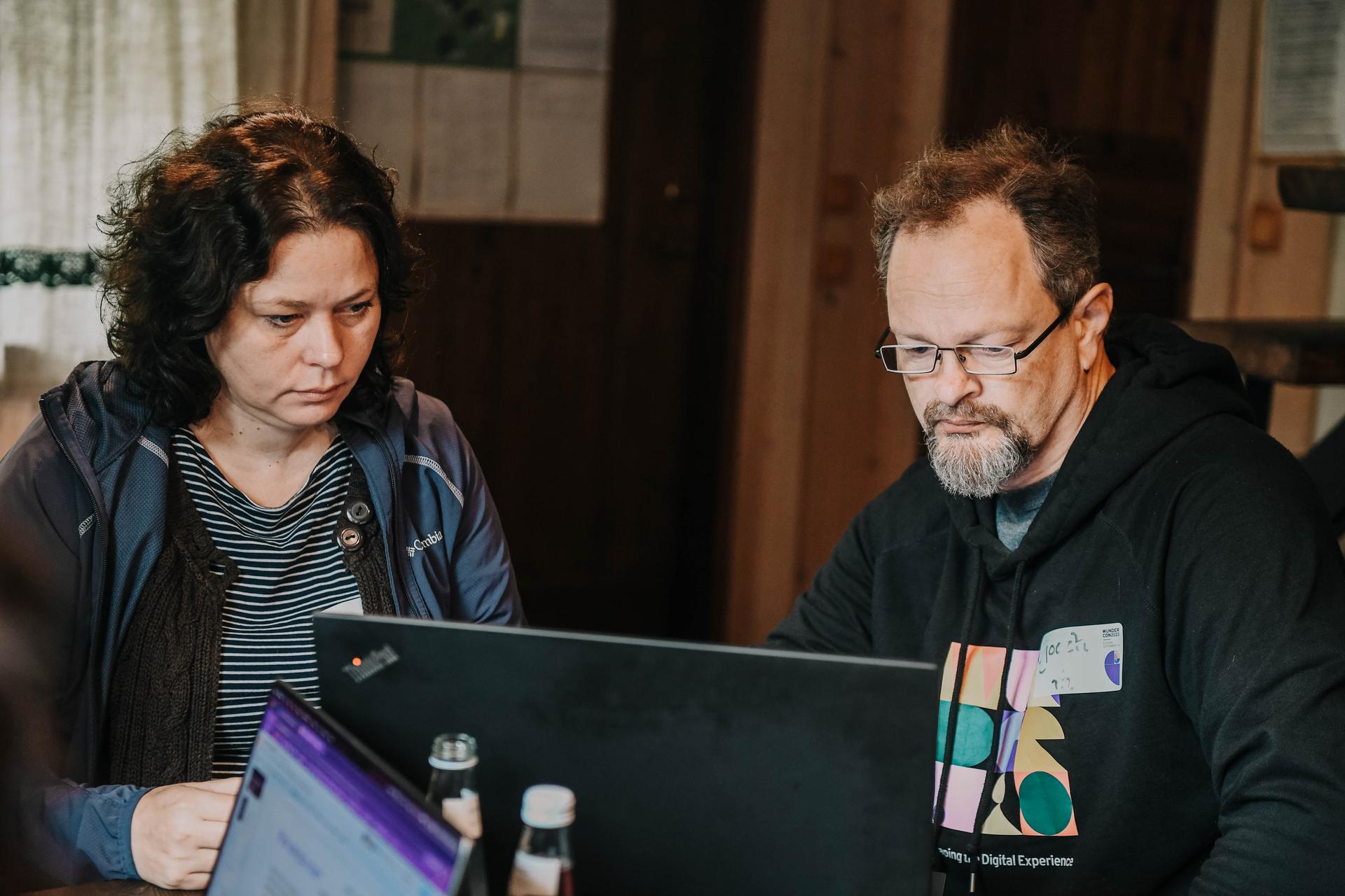 Two persons looking at one PC screen
