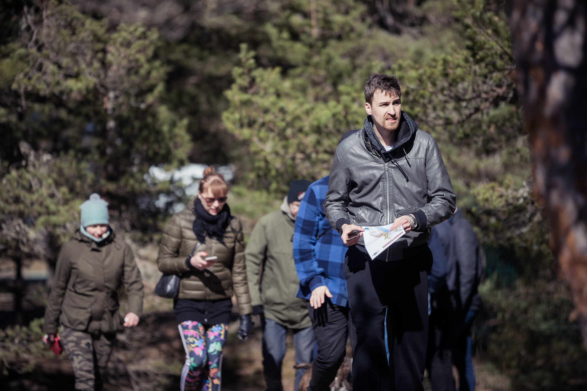 Group of people outside following a person with an orienteering map.