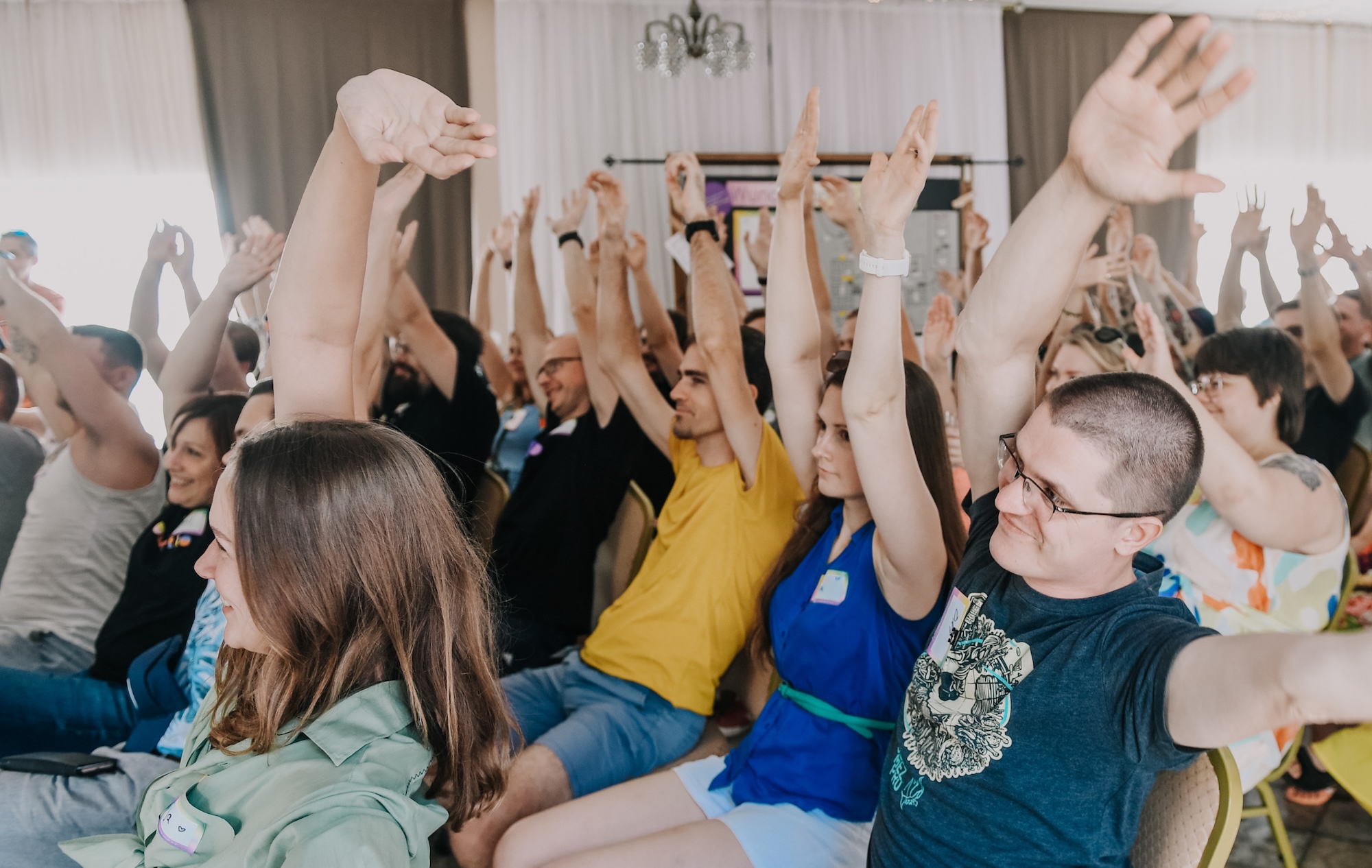 Audience raising both hands and smiling.
