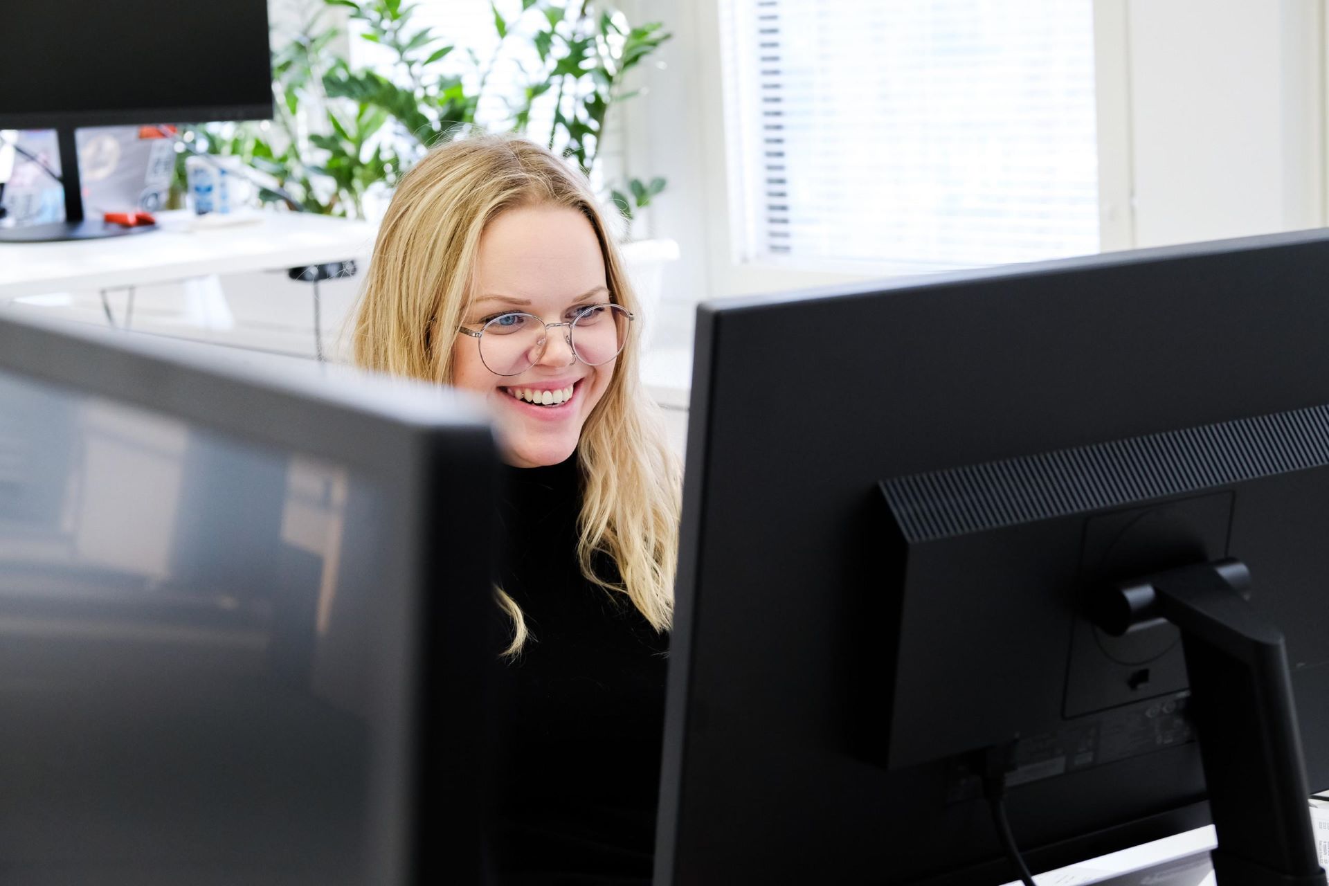 Woman sits behind a table with two computer screens