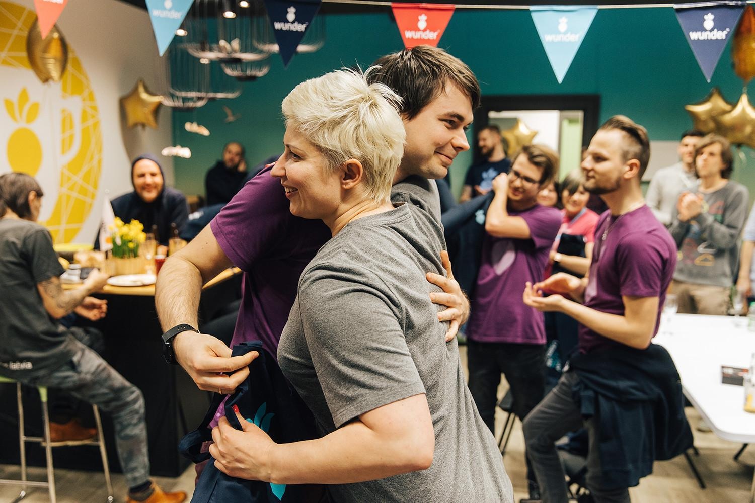 Two smiling people hugging each other