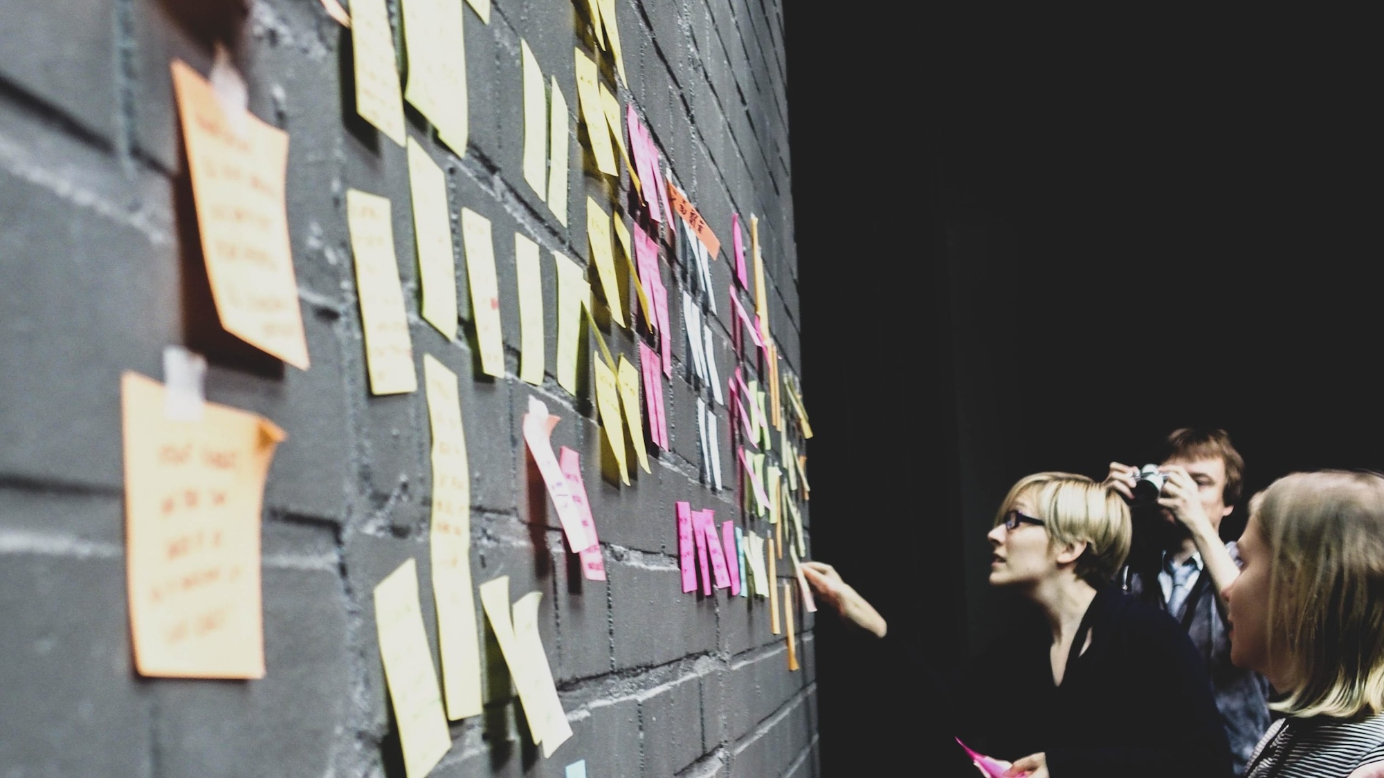 People teamworking in front of a inspiration wall in the Joyhacking event.