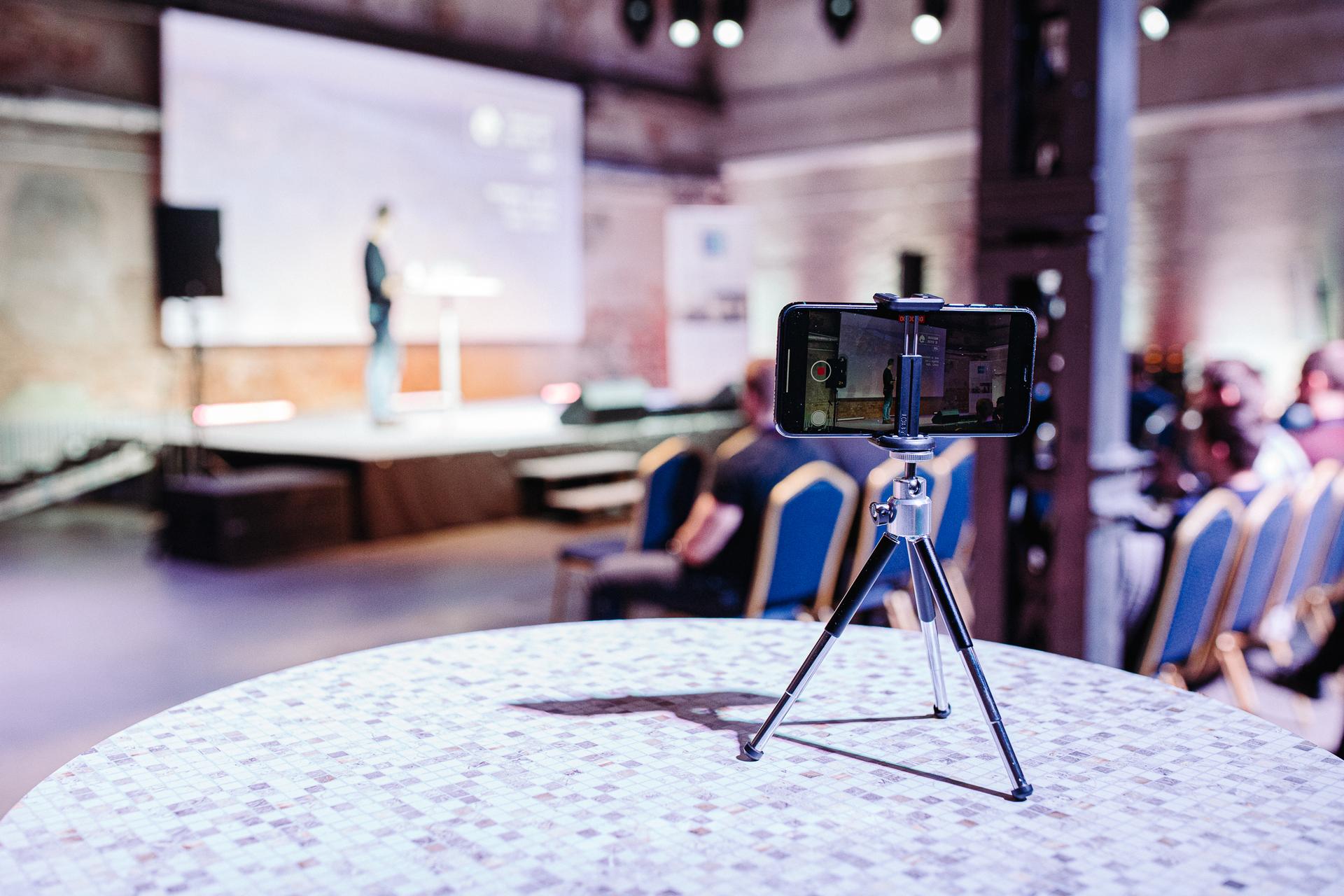 Conference hall with speaker on the stage and phone recordign the speach