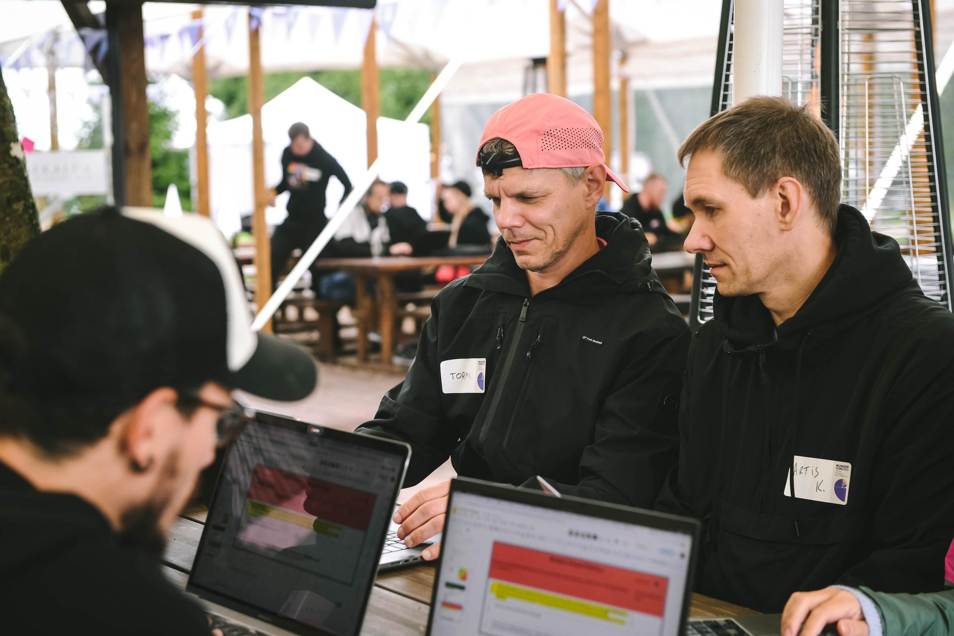 Tormi and Artis are looking at the screen